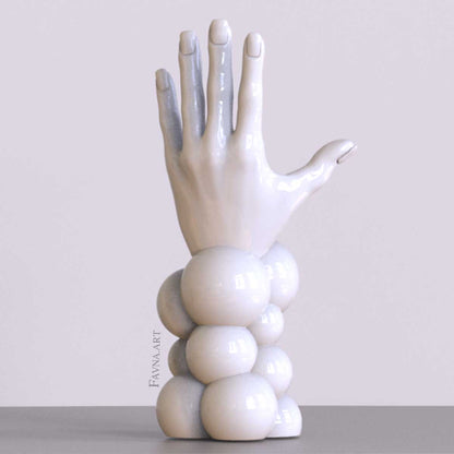 Scultura contemporanea figurativa di design per interni moderni: mano femminile con unghie smaltate e sfere astratte. Scultura artistica moderna in bianco.