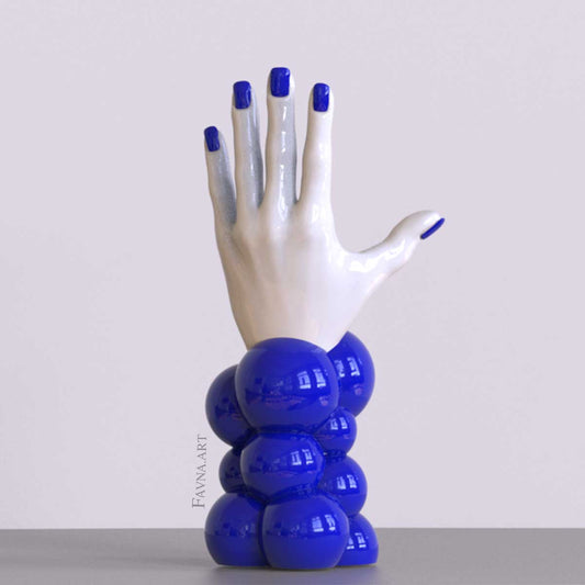 Scultura contemporanea figurativa di design per interni moderni: mano femminile con unghie smaltate e sfere astratte. Scultura artistica moderna in blue.