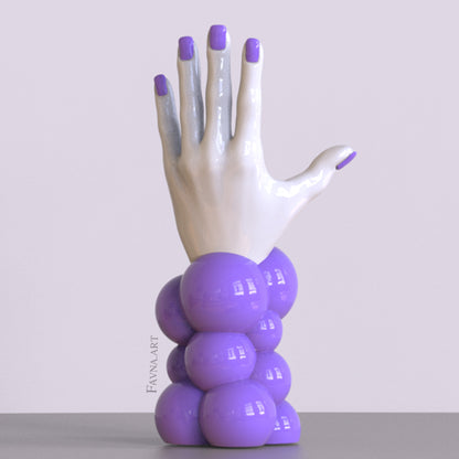 Scultura contemporanea figurativa di design per interni moderni: mano femminile con unghie smaltate e sfere astratte. Scultura artistica moderna in viola.